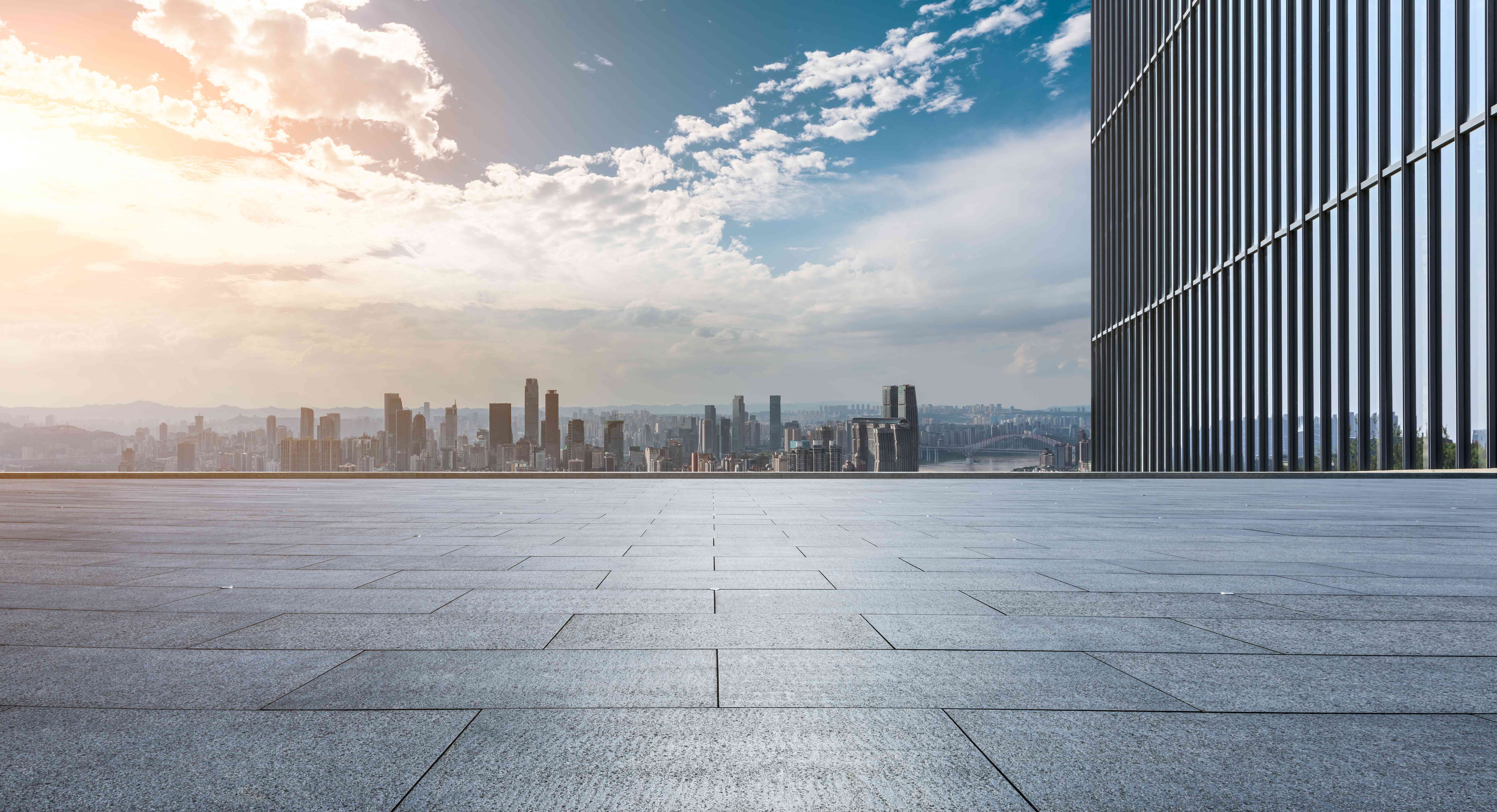 Expansive city plaza with modern building and panoramic cityscape view at sunset
